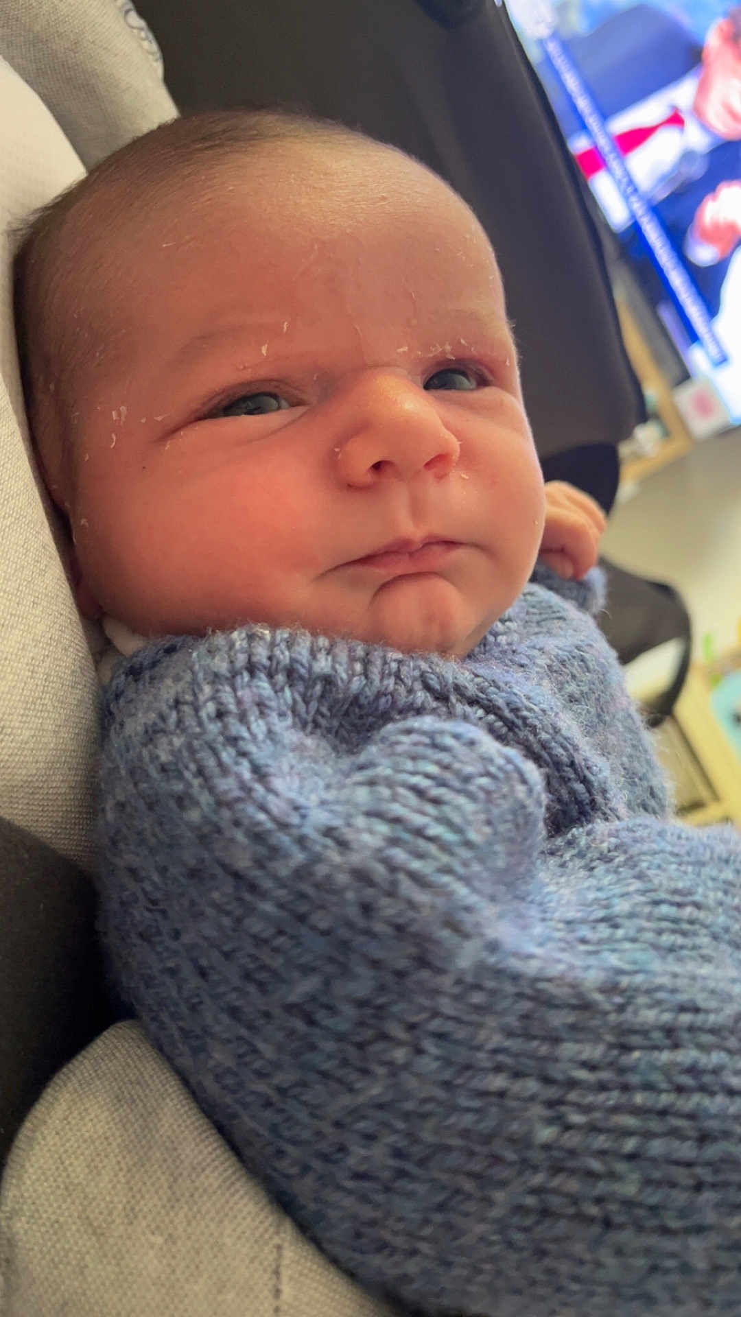 Solann participe au concours pour gagner de l'argent avec cette photo : baby, infant, face, closeup, blue_sweater, knitted_clothing, child, portrait, indoors, resting, newborn, skin, head, expression, cozy, warm_clothing, home, television, soft_light, young