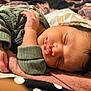 infant, baby, newborn, sleeping, face, hand, blanket, bedding, onesie, closeup, portrait, cozy, soft_texture, eyelashes, hair, skin, indoor, peaceful, pudgy, resting