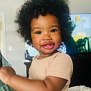 Saiyah is registered to the contest to win money with this photo: toddler, child, smile, curly_hair, afro, beige_shirt, arm, hand, living_room, television, furniture, indoor, person, portrait, happy, cute, baby, skin, closeup, cozy