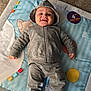 baby, smile, hoodie, pants, socks, play_mat, milestone_sticker, carpet, indoor, child, infant, clothing, face, person, cute, happy, nike, fabric, toy, colorful