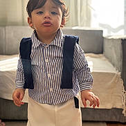 Zayn Luqman a rejoint le concours — aidez-le/la à gagner de superbes lots ! toddler, child, indoor, striped_shirt, pants, suspenders, living_room, carpet, sofa, curtains, window, young_child, standing, portrait, person, cute, home, casual_clothing, floor, natural_light