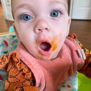 Ivy joined the competition — help win amazing prizes! baby, blue_eyes, bib, baby_food, pink_bib, orange_food_stain, baby_seat, curious_expression, open_mouth, close_up, infant, child, clothing, indoor, face, person, cute, young_child, surprised, feeding_time