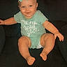 baby, child, infant, girl, sitting, couch, bow, hair_accessory, onesie, green_clothing, smiling, happy, portrait, indoor, furniture, barefoot, outstretched_arms, dark_background, social_media_screenshot, photography