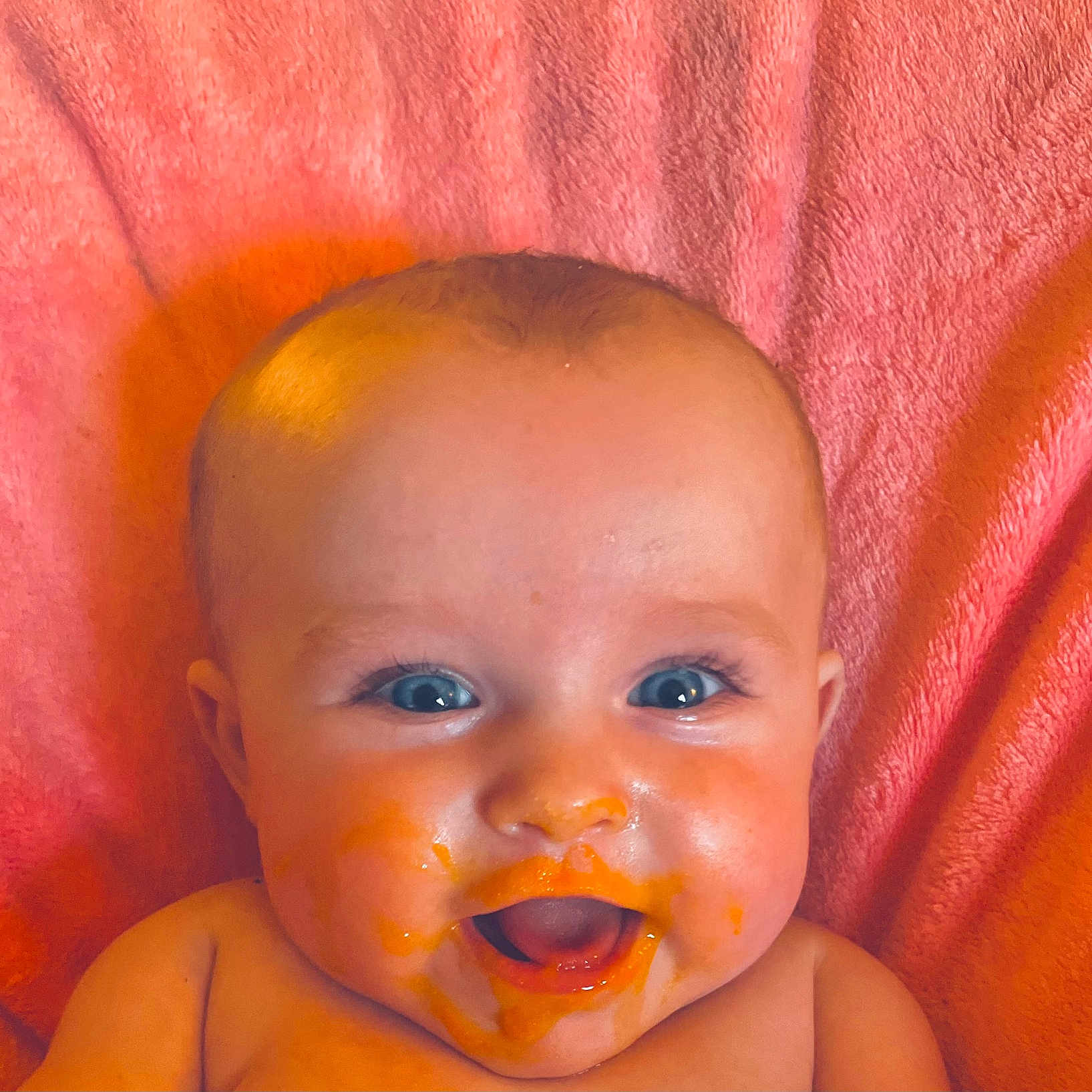 Chloe Ann is registered to the contest to win money with this photo: baby, blanket, blue_eyes, cheeks, child, closeup, cute, expression, face, food, happy, head, infant, messy, mouth_open, orange_puree, pink, portrait, skin, smiling