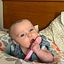 Chloe Ann joined the competition — help win amazing prizes! baby, blue_eyes, pink_spoon, baby_food, cushioned_seat, colorful_pattern, wooden_headboard, bed, blanket, indoor, person, child, infant, hand, face, curious, feeding, clothing, comfort, home