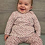 baby, child, smiling, pajamas, floral_pattern, sitting, couch, blanket, footwear, indoors, happy, cute, portrait, cozy, clothing, person, infant, soft_texture, head, face