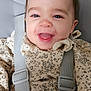 baby, smiling, child, infant, high_chair, straps, clothing, dress, floral_pattern, face, happy, cute, indoors, person, head, hair_accessory, seat, babywear, closeup, safety