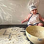 apron, baby, chef_hat, child, cooking, cute, face, flour, hand, indoor, infant, kitchen, messy, mixing_bowl, person, playful, small, smile, table, white