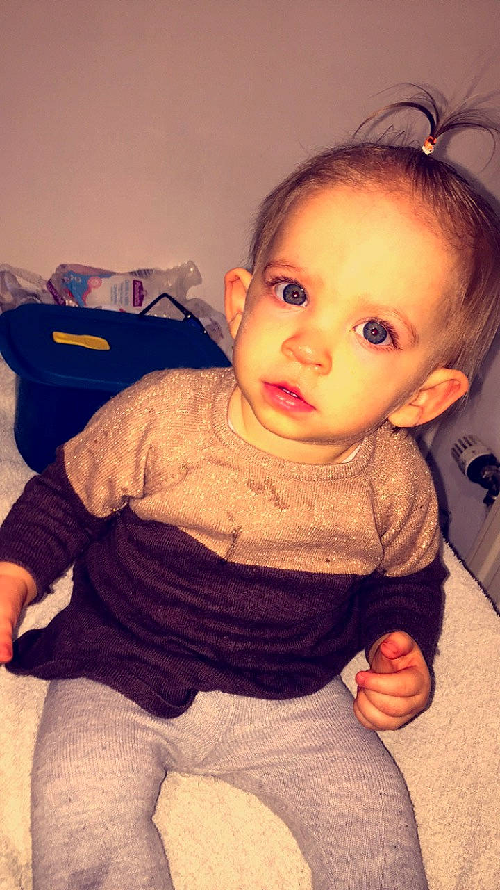 Kélya participe au concours pour gagner de l'argent avec cette photo : arm, baby, cheek, child, chin, cool, ear, eye, face, forehead, head, lip, mouth, nose, person, sitting, skin, sleeve, smile, toddler