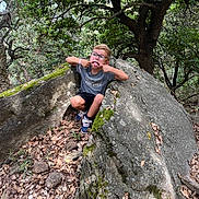 Ewen participe au concours pour gagner de l'argent avec cette photo : boy, candid, casual_clothing, child, daylight, forest, fun, glasses, leaves, moss, nature, outdoor, playful, rock, shorts, silly_face, smile, sneakers, trees, young