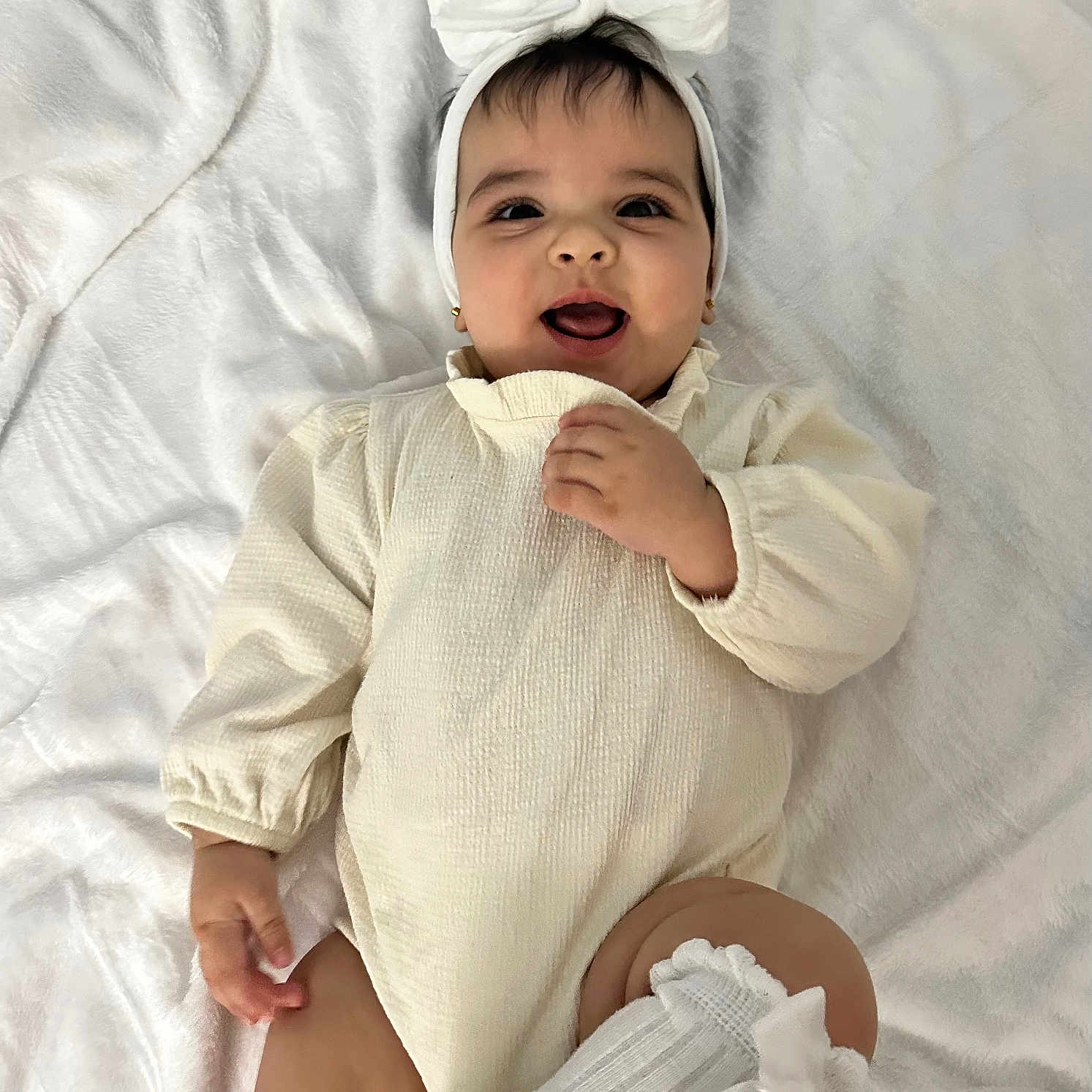 Aitana is registered to the contest to win money with this photo: baby, infant, smiling, headband, bow, white_clothing, socks, blanket, cute, happy, portrait, child, earrings, lying_down, soft_texture, adorable, indoors, one_person, baby_girl, cozy