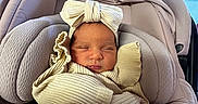 Aitana joined the competition — help win amazing prizes! baby, newborn, infant, car_seat, headband, bow, clothing, sleeping, indoors, window, cushion, soft_fabric, portrait, person, cozy, child, cute, wrapped, resting, peaceful