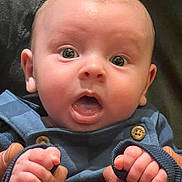 Theo joined the competition — help win amazing prizes! baby, blue_outfit, child, close_up, clothing, cute, expression, face, hands, holding, human, indoor, infant, newborn, open_mouth, person, portrait, skin, wide_eyes, wooden_buttons