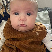Perle a rejoint le concours — aidez-le/la à gagner de superbes lots ! baby, closeup, face, child, corduroy, brown, clothing, cute, indoor, infant, person, portrait, soft, texture, young, eyes, cheeks, sitting, cushion, comfortable