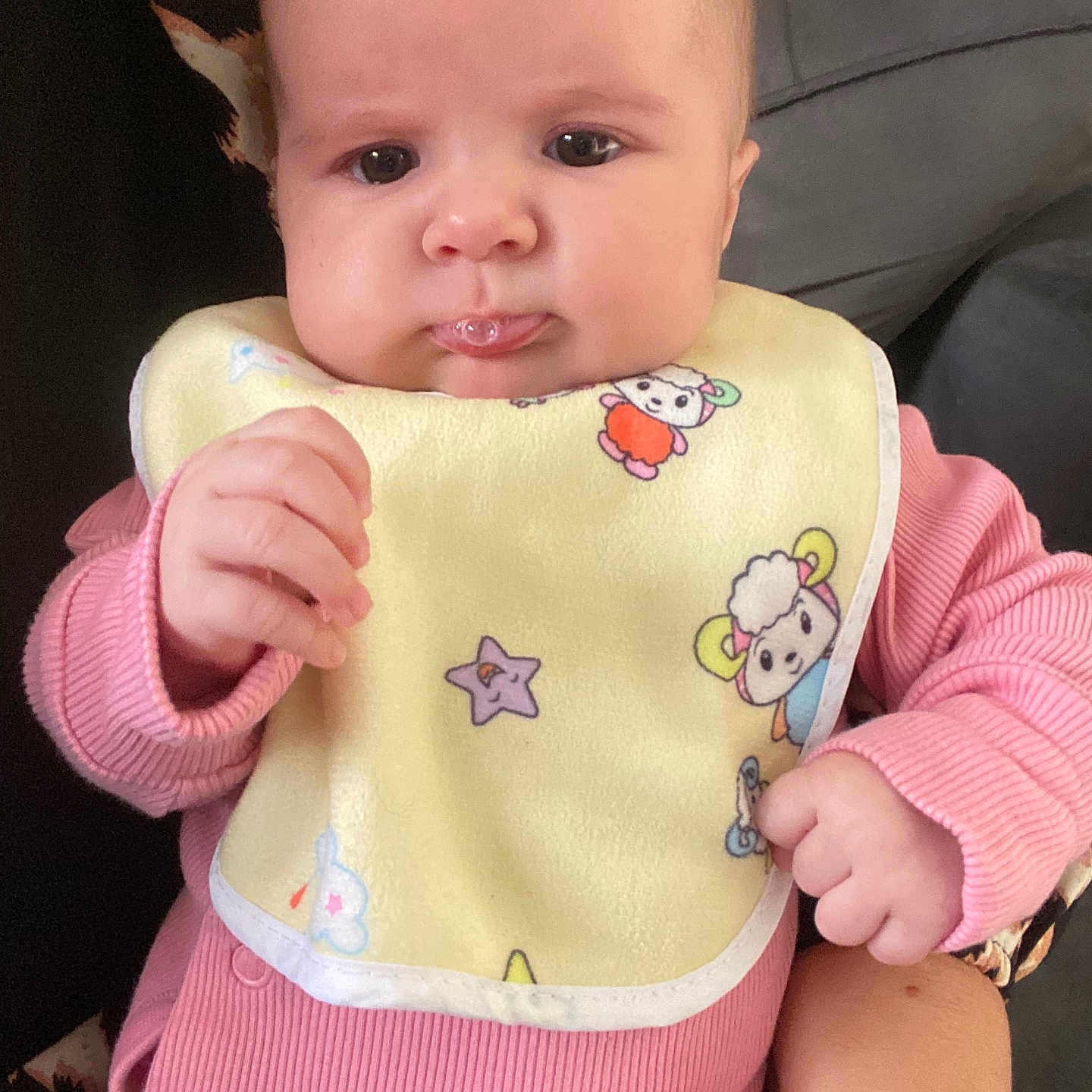 Perle a rejoint le concours — aidez-le/la à gagner de superbes lots ! adult_arm, baby, bib, child, closeup, couch, cute, drool, expression, face, hand, holding, indoor, infant, patterned_cushion, person, pink_clothing, seated, skin, young