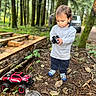 toddler, child, forest, toy_truck, remote_control, bird, trees, leaves, ground, hoodie, shoes, outdoor, nature, vehicle, curious, standing, daylight, person, play, exploration