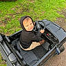 Marcelo joined the competition — help win amazing prizes! toddler, child, toy_car, black_hoodie, outdoor, grass, greenery, play, smile, happy, vehicle, steering_wheel, casual_clothing, boots, dirt_path, seat, seatbelt, parked_car, fun, young_child