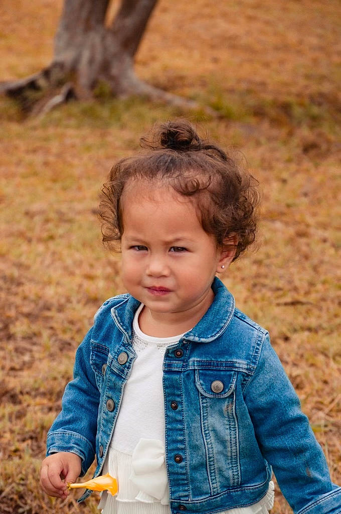 Taelyn Louise joined the competition — help win amazing prizes! baby_toddler_clothing, child, facial_expression, grass, happy, human, jacket, light, people, people_in_nature, person, photograph, plant, skin, sleeve, standing, summer, sunlight, toddler, tree