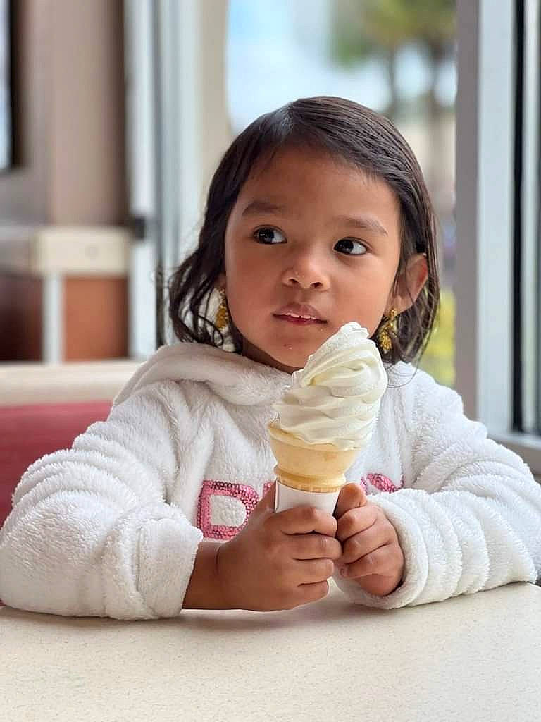 Allyson is registered to the contest to win money with this photo: child, cream, dairy, dessert, drinkware, face, finger, food, food_craving, frozen_dessert, gesture, hand, happy, ice_cream, ice_cream_cone, icing, ingredient, person, sweetness, tableware