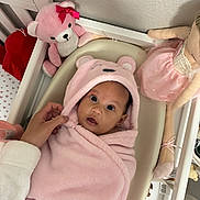Alaia joined the competition — help win amazing prizes! baby, newborn, infant, pink, hooded, blanket, bassinet, crib, teddy_bear, stuffed_animal, doll, nursery, sleeping_area, portrait, wide_eyed, baby_clothing, adult_hand, indoor, cozy, family