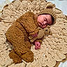 baby, sleeping, bear_costume, crocheted_blanket, teddy_bear, infant, cute, cozy, soft_texture, handmade, knitwear, child, peaceful, resting, portrait, warm_colors, fuzzy_clothing, adorable, laying_down, nursery