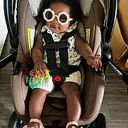 Zanai joined the competition — help win amazing prizes! baby, car_seat, sunglasses, toy, sandals, floor, clothing, child, person, infant, footwear, play, cute, smile, indoor, strap, seat, accessory, legs, headwear