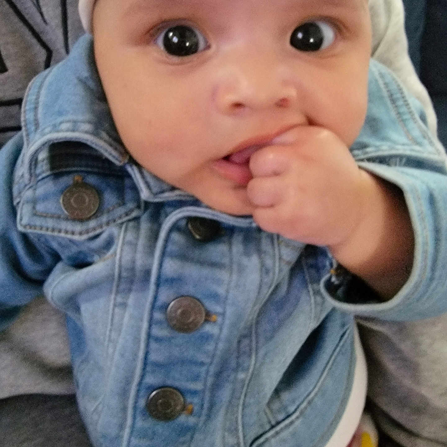 Amelia is registered to the contest to win money with this photo: baby, casual_wear, child, clothing, curious, cute, denim_jacket, eyes, face, finger_in_mouth, hand, headband, indoor, infant, person, portrait, sitting, soft_focus, wide_eyes, young_child