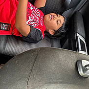 Jonah Lokai Juda joined the competition — help win amazing prizes! child, boy, car_interior, seat, seatbelt, red_clothing, short_hair, smile, portrait, casual, indoor, young, relaxed, candid, person, automobile, seat_cover, black_hair, cheerful, clothing