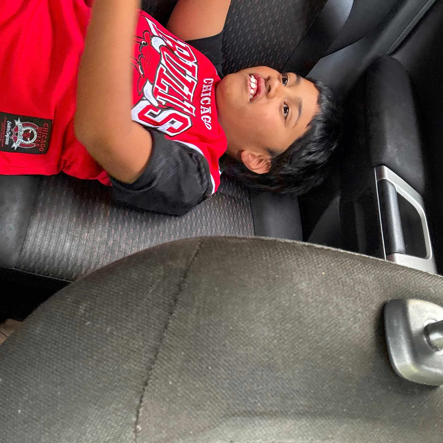 Jonah Lokai Juda joined the competition — help win amazing prizes! child, boy, car_interior, seat, seatbelt, red_clothing, short_hair, smile, portrait, casual, indoor, young, relaxed, candid, person, automobile, seat_cover, black_hair, cheerful, clothing
