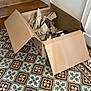 cat, cardboard_box, crumpled_paper, tile_floor, patterned_floor, stairs, wooden_stairs, indoor, pet, animal, curious, peeking, cozy, home, flooring, resting, one_eye_visible, brown, white, playful