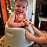 baby, infant, smiling, orange_clothing, high_chair, kitchen, countertop, granite, wooden_cabinets, dried_vegetables, coffee_maker, happy, seated, child, indoors, face, furniture, cute, person, portrait