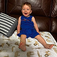 Javan joined the competition — help win amazing prizes! toddler, child, smiling, blue_outfit, leather_couch, pillow, blanket, animal_print, happy, sitting, indoor, cute, young_child, furniture, home, portrait, cozy, playful, person, baby