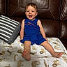 toddler, child, smiling, blue_outfit, leather_couch, pillow, blanket, animal_print, happy, sitting, indoor, cute, young_child, furniture, home, portrait, cozy, playful, person, baby