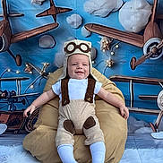 Javan Mccormick is registered to the contest to win money with this photo: airplanes, aviator_hat, baby, beanbag, blue_background, child, clouds, costume, cute, decor, fun, indoor, infant, playful, portrait, seat, smiling, socks, white_shirt, young