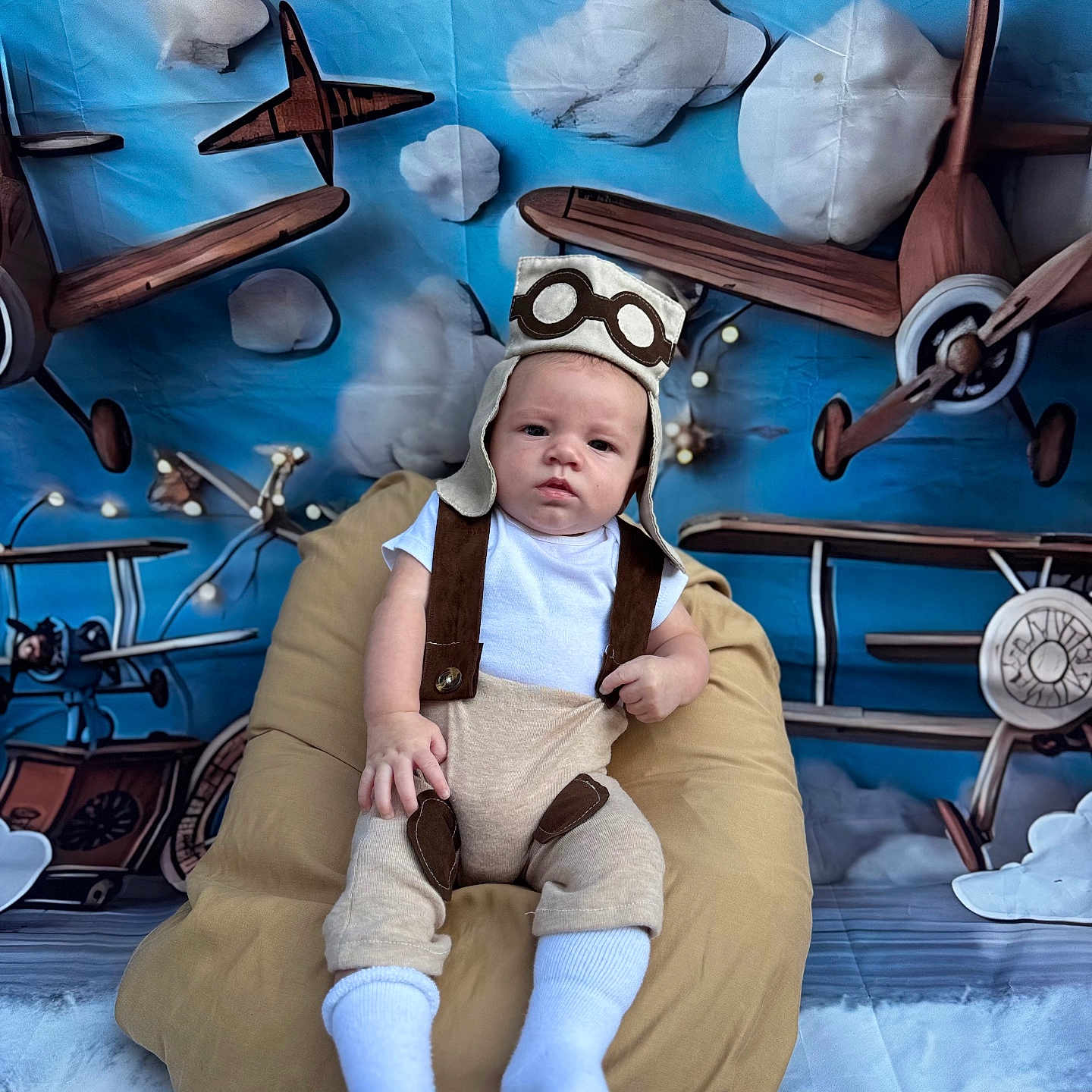 Javan Mccormick joined the competition — help win amazing prizes! airplanes, baby, background, bean_bag, blue_sky, child, clouds, costume, cute, fabric, floor, indoor, infant, photography, pilot_hat, playful, portrait, seated, suspenders, white_socks
