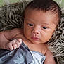 Cobee is registered to the contest to win money with this photo: baby, infant, face, eyes, blanket, pattern, animal_print, hand, skin, fur_cushion, closeup, portrait, newborn, curious, indoors, soft_texture, resting, expression, young_child, cozy