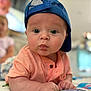 baby, child, blue_cap, curious, face, indoor, infant, person, portrait, tummy, young_child, clothing, short_sleeve, cute, wide_eyes, focus, background_blur, skin, hands, expression