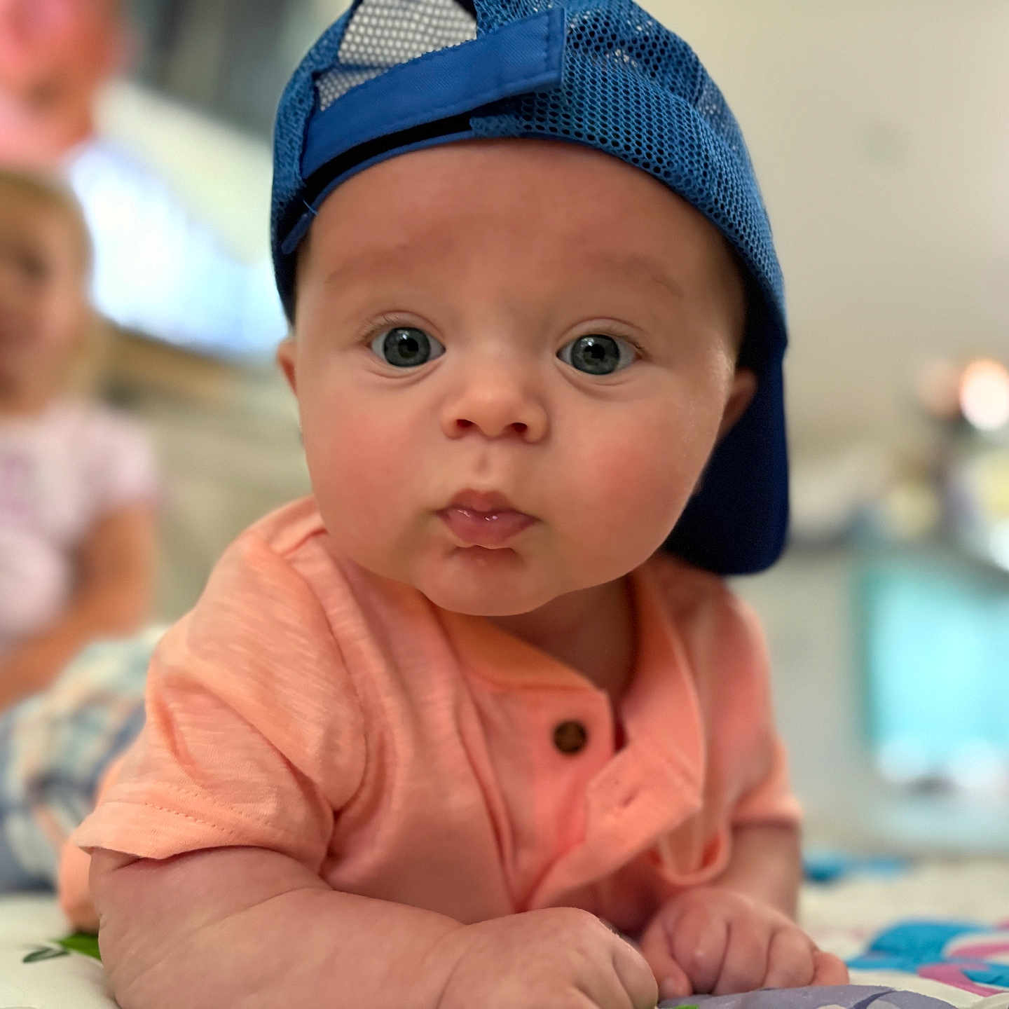 Easton is registered to the contest to win money with this photo: baby, background_blur, blue_cap, child, clothing, curious, cute, expression, face, focus, hands, indoor, infant, person, portrait, short_sleeve, skin, tummy, wide_eyes, young_child