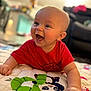 Easton is registered to the contest to win money with this photo: baby, child, smiling, laughing, red_shirt, quilt, colorful, indoor, face, happy, crawling, young_child, cute, cheerful, person, infant, home, soft_lighting, blanket, playtime
