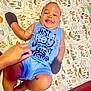 baby, boy, smiling, blue_outfit, blanket, hand, tongue_out, infant, patterned_blanket, cute, lying_down, happy, child, indoors, clothing, person, skin, foot, arm, playful