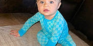 Emmett is registered to the contest to win money with this photo: baby, child, blue_onesie, carpet, indoor, couch, leather_furniture, floor, portrait, sitting, curious, wide_eyes, blond_hair, small_hands, bare_feet, expression, young, cute, home, infant