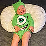 baby, child, smiling, green_clothing, hat, pillow, couch, happy, cute, infant, face, legs, sitting, indoor, playful, portrait, one_person, young_child, funny_outfit, expression
