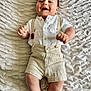 baby, infant, smiling, lying_down, suspenders, shorts, white_shirt, cute, happy, child, portrait, indoors, blanket, texture, skin, person, young, one_person, casual_clothing, relaxed