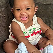 Jahzara joined the competition — help win amazing prizes! baby, child, smiling, cute, sitting, couch, white_clothing, socks, cherry_pattern, happy, indoors, infant, portrait, cute_outfit, toddler, dark_background, hand, face, person, young_child